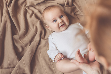 Image showing mom dresses the baby on the bed