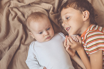 Image showing little boy playing with newborn on the bed