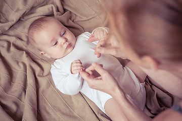 Image showing mom dresses the baby on the bed