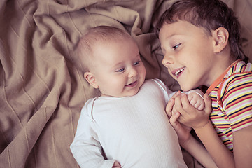 Image showing little boy playing with newborn on the bed