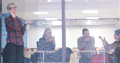 Image showing Business Woman Looking Through A Window And using On A Cell Phon