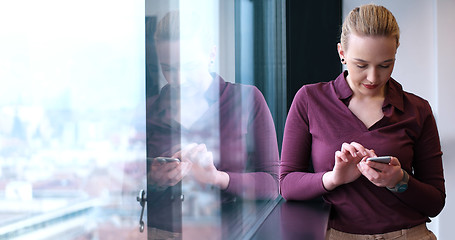 Image showing Elegant Woman Using Mobile Phone by window in office building