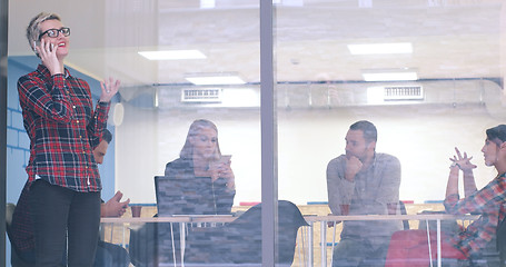 Image showing Business Woman Looking Through A Window And using On A Cell Phon