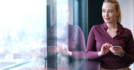 Image showing Elegant Woman Using Mobile Phone by window in office building