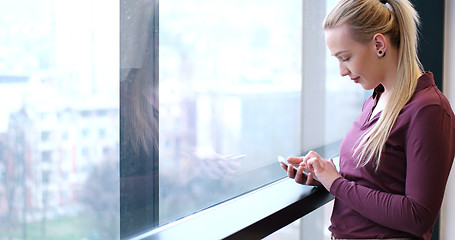 Image showing Elegant Woman Using Mobile Phone by window in office building