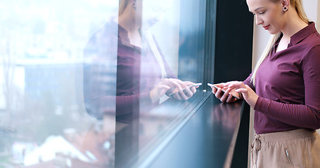 Image showing Elegant Woman Using Mobile Phone by window in office building