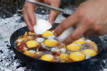 Image showing Fried eggs cooking on camp fire in smoke