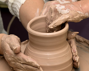 Image showing Two women in process of making clay vase on pottery wheel