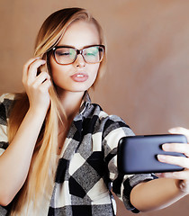 Image showing young pretty blond woman with smartphone posing smiling, making 