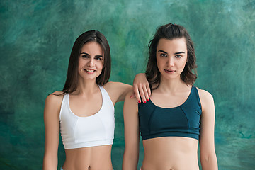 Image showing Two young sporty women posing at gym.