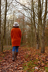 Image showing Woman in warm cardigan and hat walking through autumnal woodland