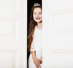 Image showing little cute girl at home, opening door well-dressed in white dress, adorable milk fairy teeth, curious child 