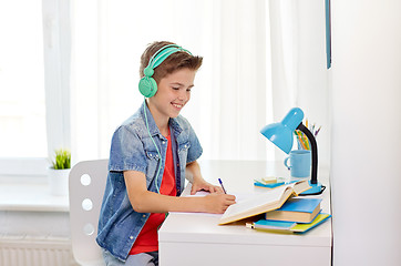 Image showing student boy in headphones writing to notebook