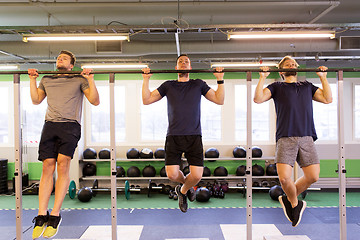 Image showing group of young men doing pull-ups in gym