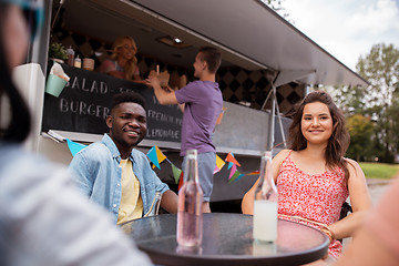 Image showing friends with drinks sitting at table at food truck