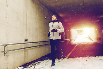 Image showing happy man running along subway tunnel in winter