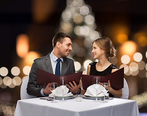 Image showing smiling couple with menus at christmas restaurant