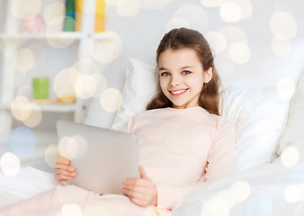 Image showing happy girl in bed with tablet pc over lights