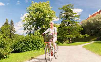 Image showing happy senior woman riding bicycle at summer park