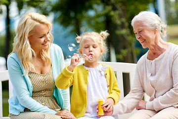 Image showing happy family blowing soap bubbles at park