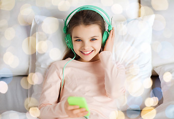 Image showing girl with headphones listening to music in bed