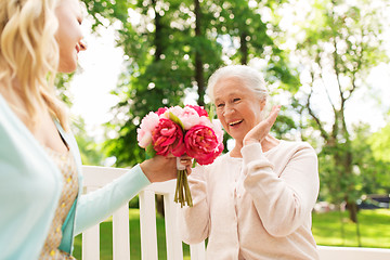 Image showing daughter giving flowers to senior mother at park