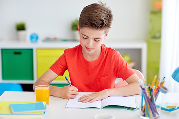 Image showing happy student boy writing to notebook at home