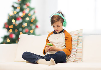 Image showing boy with smartphone and headphones at christmas