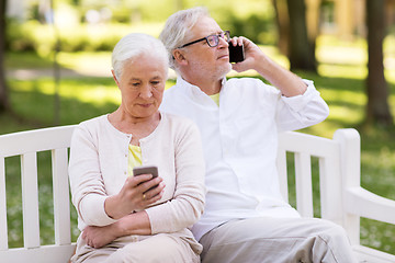 Image showing happy senior couple with smartphones at park