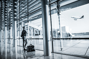 Image showing Young woman waiting at airport, looking through the gate window.