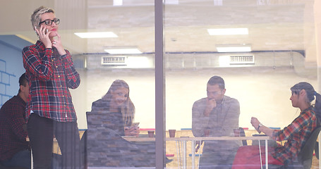 Image showing Business Woman Looking Through A Window And using On A Cell Phon