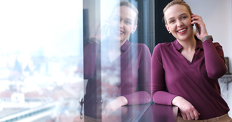 Image showing Elegant Woman Using Mobile Phone by window in office building