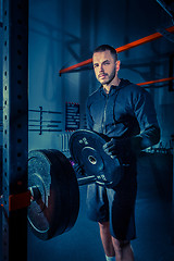 Image showing Portrait of super fit muscular young man working out in gym with barbell