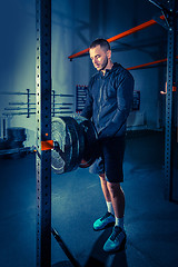 Image showing Portrait of super fit muscular young man working out in gym with barbell