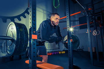 Image showing Portrait of super fit muscular young man working out in gym with barbell