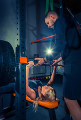 Image showing Fit young woman lifting barbells looking focused, working out in a gym