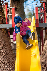 Image showing Happy three-year baby girl in jacket on slide