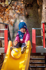 Image showing Happy three-year baby girl in jacket on slide