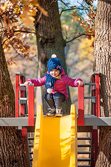 Image showing Happy three-year baby girl in jacket on slide