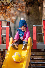 Image showing Happy three-year baby girl in jacket on slide