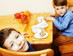 Image showing little cute boys eating dessert on wooden kitchen. home interior