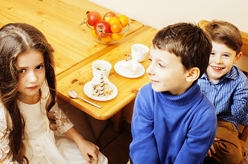 Image showing little cute boys eating dessert on wooden kitchen. home interior