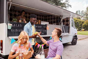 Image showing happy friends with drinks eating at food truck