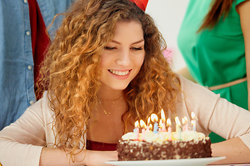 Image showing happy woman with candles on birthday cake at party