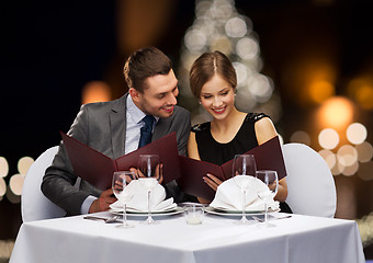 Image showing smiling couple with menus at christmas restaurant