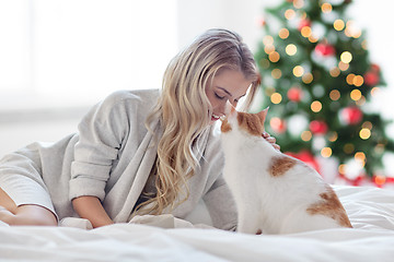 Image showing happy young woman with cat in bed at christmas