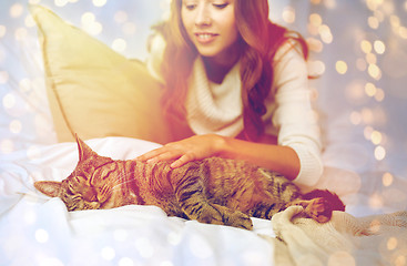 Image showing happy young woman with cat lying in bed at home