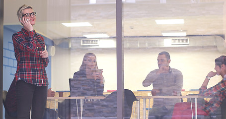 Image showing Business Woman Looking Through A Window And using On A Cell Phon