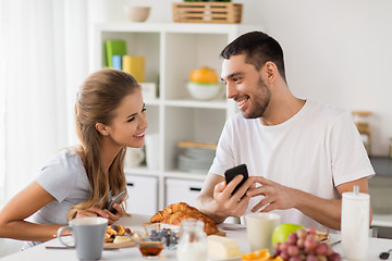 Image showing couple with smartphones having breakfast at home