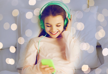 Image showing girl with headphones listening to music in bed